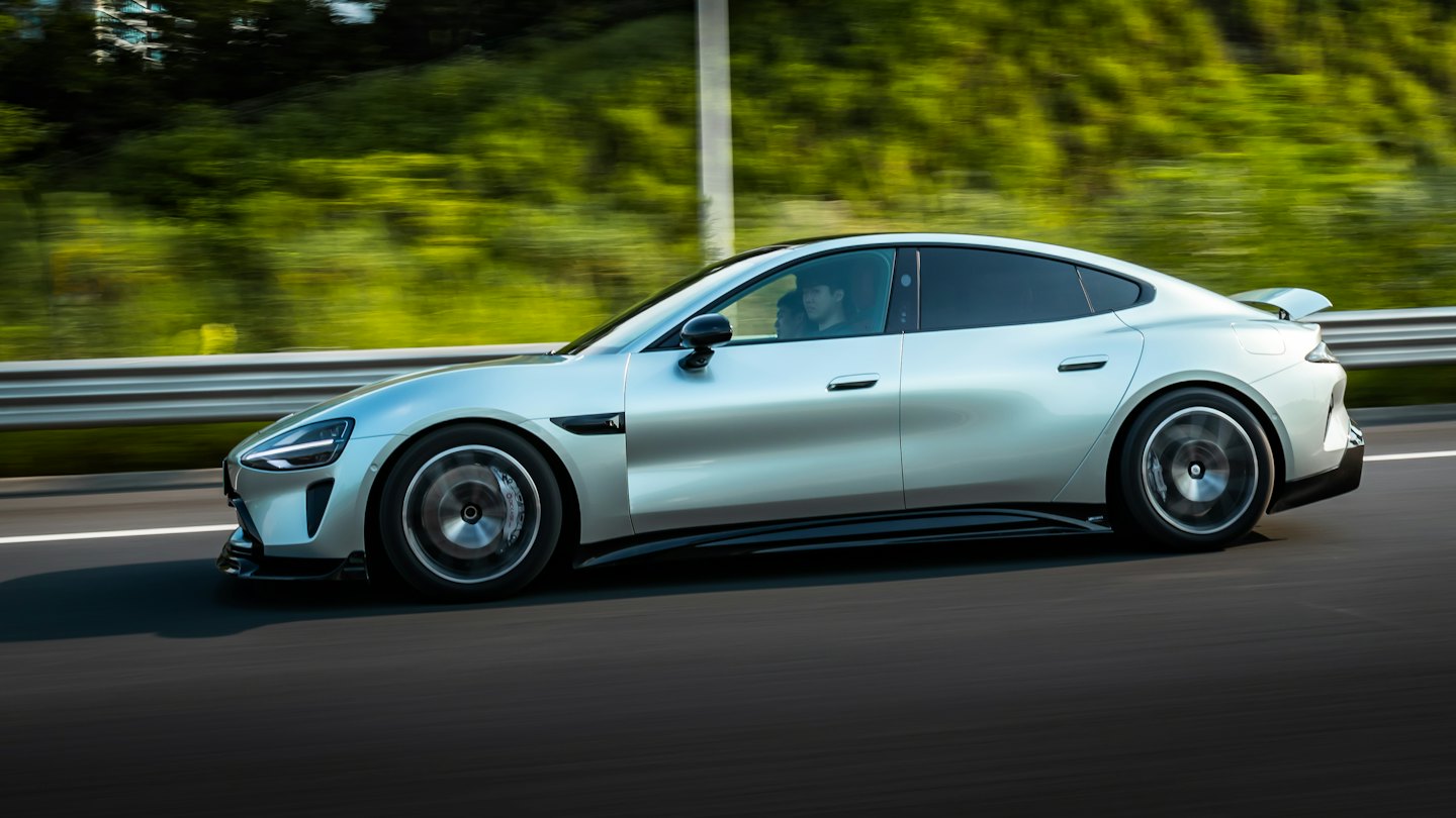 Elegancki srebrny samochód elektryczny jedzie szybko autostradą.